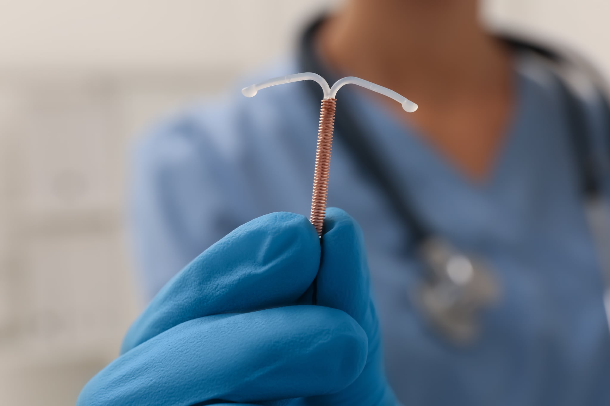Doctor holding an IUD against a blurred background.