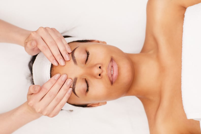 Above view portrait of beautiful mixed-race woman enjoying face massage in luxury spa, copy space