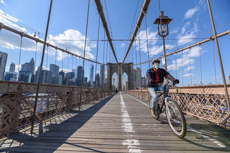 NEW YORK, NY - APRIL 15: A man wearing a protective mask rides a bicycle on the Brooklyn Bridge during the coronavirus pandemic on April 15, 2020 in New York City. COVID-19 has spread to most countries around the world, claiming over 134,000 lives lost wi
