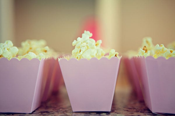 Have a popcorn bar station for guests to add their own seasonings. And mini pink boxes make it even cuter.