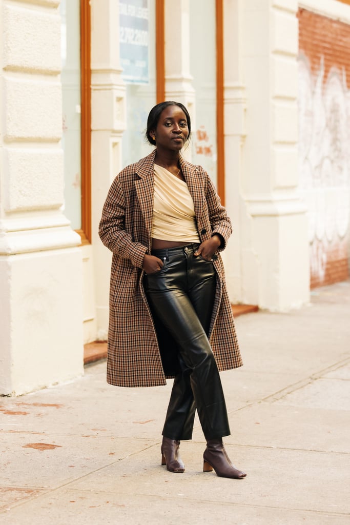 Shelcy Joseph in a one-shoulder ruched Norma Kamali top worn over black Nanushka leather jeans, and accessorised with Mansur Gavriel's Chain Elegant bag, and a plaid coat from The Kooples.
