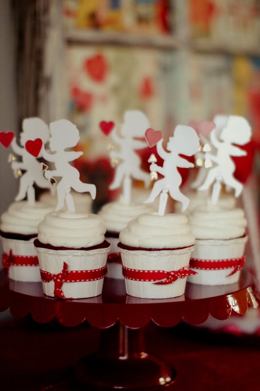 Even though the event was about decorating cookies, it wouldn't have been a Valentine's Day party without some red velvet cupcakes. The desserts were finished off with a Cupid cupcake topper and red ribbon. 
Source: Jenny Cookies