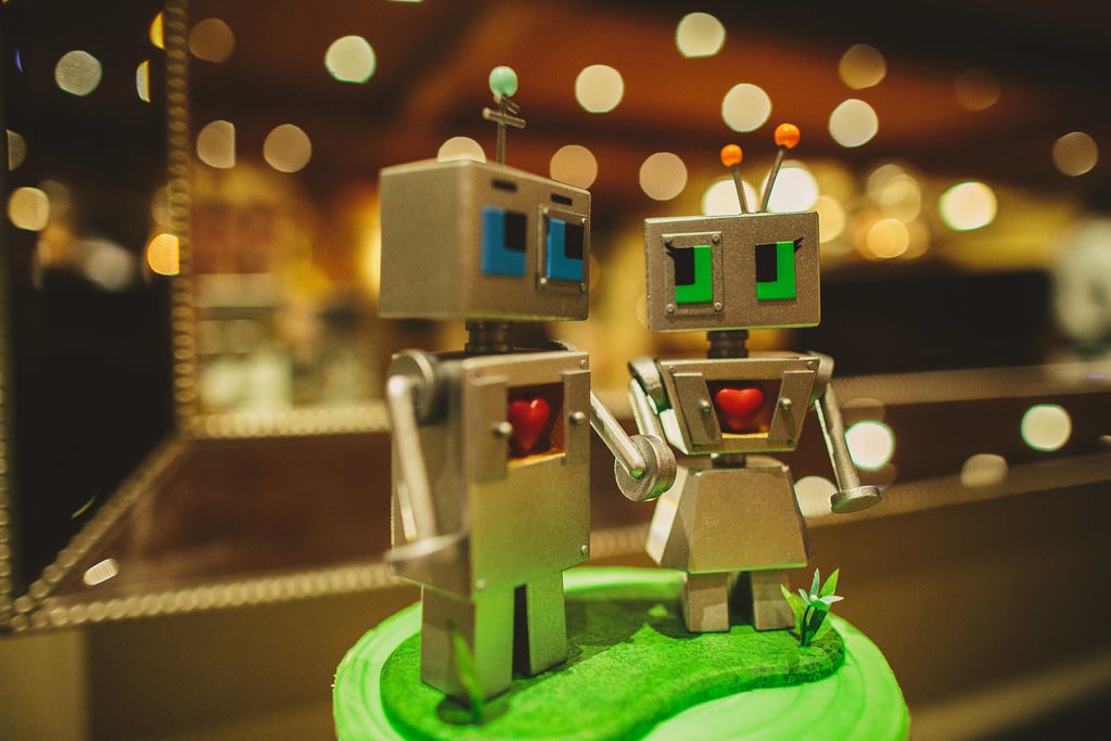 A tiny green cake is topped off with humorous robot wedding toppers.