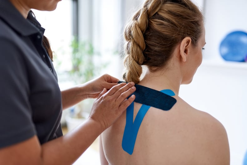 physical therapist putting kinesiology tape on patient; what is kinesiology tape and how does it work?