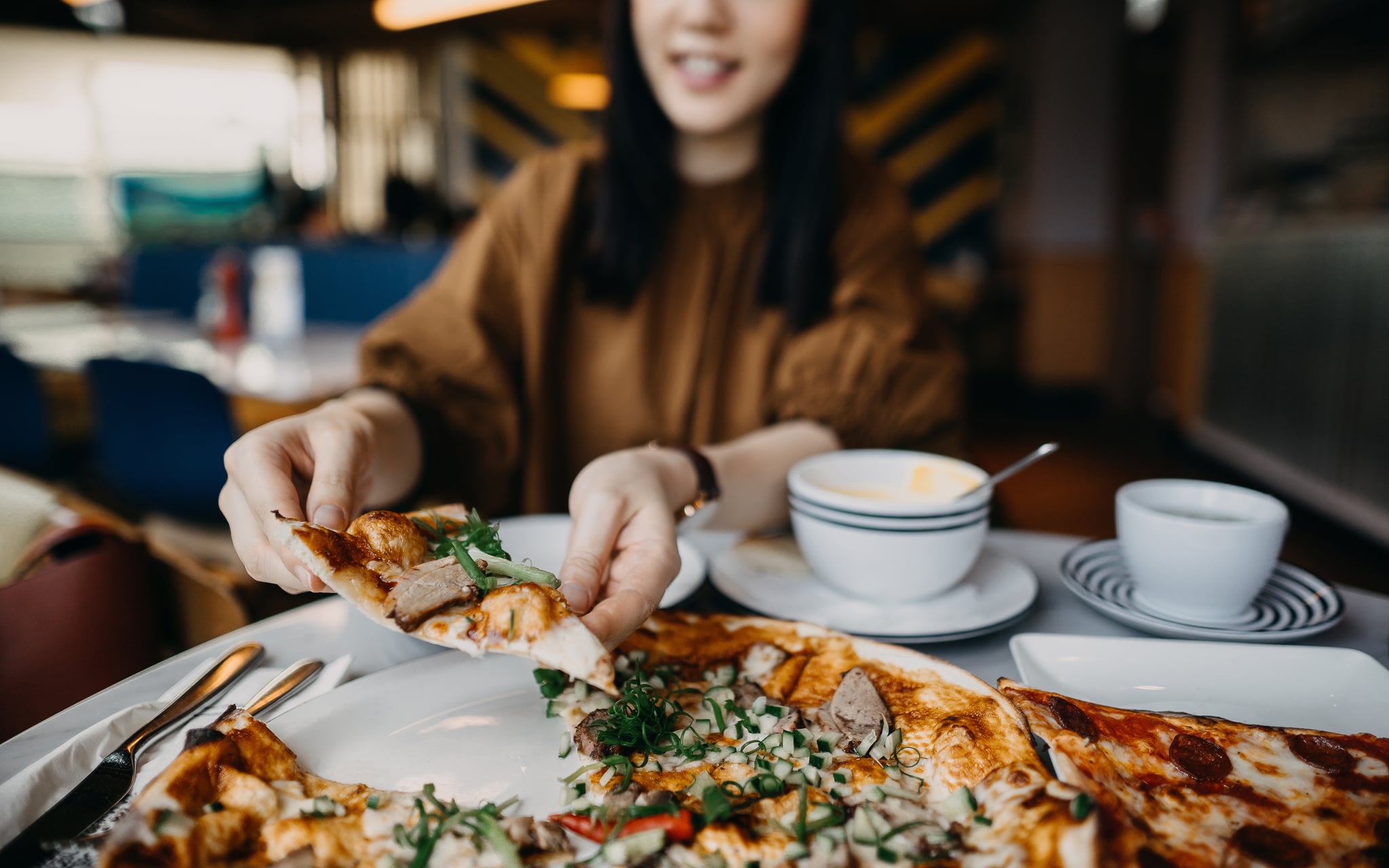 Close up of young woman enjoying meal and eating freshly made pizza in a restaurant