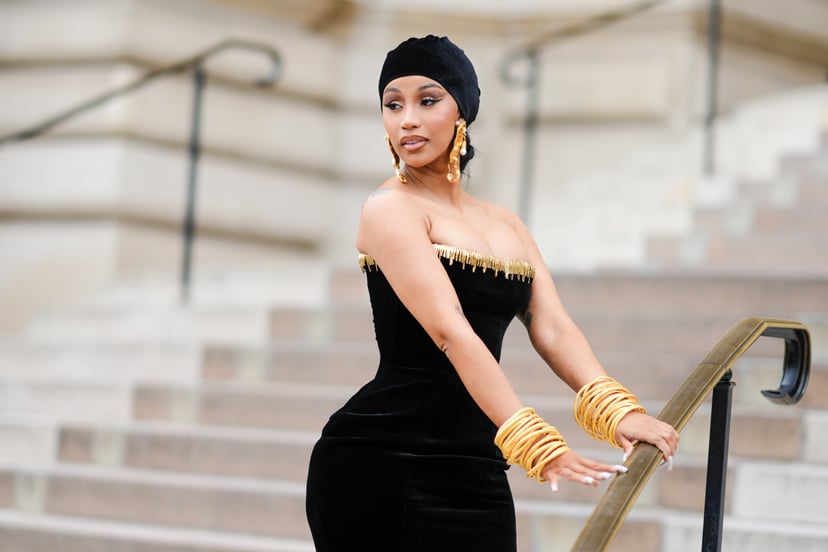 PARIS, FRANCE - JULY 03: Cardi B wears a black velvet scarf as a hat from Schiaparelli, gold large ears and white pearls pendant earrings from Schiaparelli, a black velvet with embroidered gold metallic shoulder-off borders / long tube dress from Schiapar