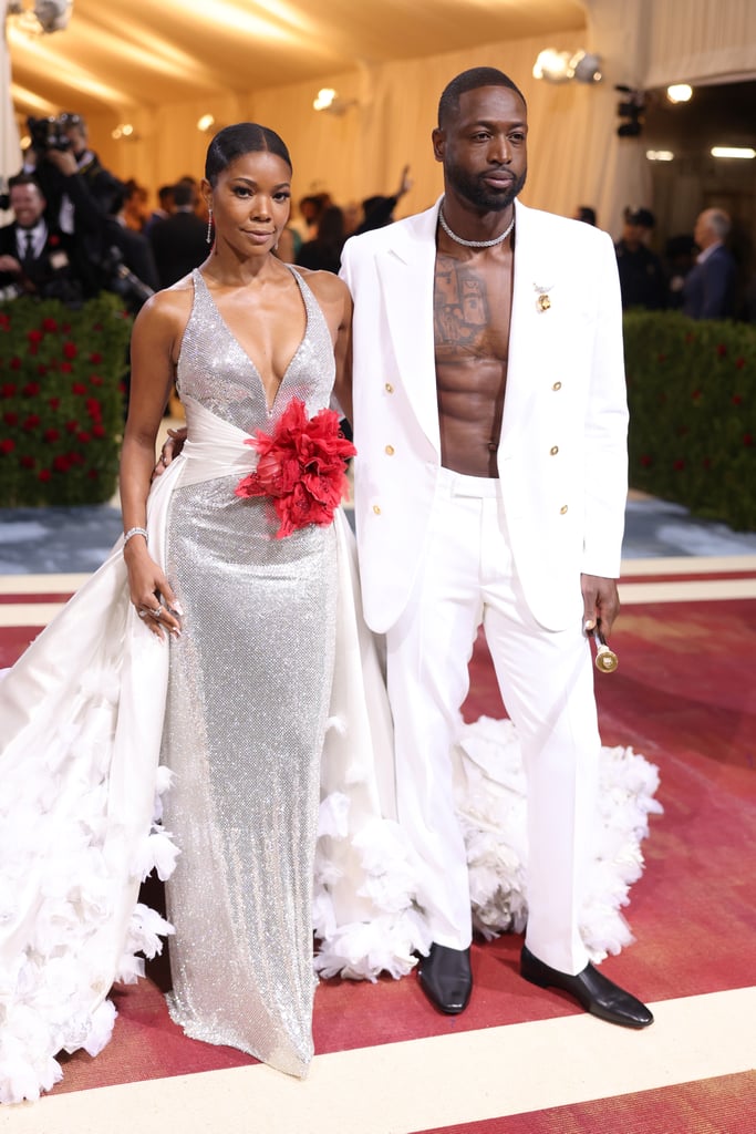 The queen and king have entered the building. On May 2, Gabrielle Union and Dwyane Wade made a stylish appearance at the 2022 Met Gala. Gracing the stairs of the Metropolitan Museum of Art, Kaavia's parents posed for photos and looked fabulous for the "Gilded Glamour" event. Union wore a silver Atelier Versace dress that featured a plunging neckline; a long, white feathered train; and a red, embellished flower wrapped around her waist. Wade opted for a modern, regal look in a white Versace suit adorned with gold buttons and a large brooch. He commanded attention with his open blazer and shirtless look as he carried a black Versace walking stick and wore a Vacheron Constantin watch.
Union is a red carpet expert, but at this year's Met Gala, her style choice had a deeper meaning. In an interview with Vogue, she said her outfit honored the late actress Diahann Carroll, "a symbol of opulence and if you will, a gilded glamour." Union said, "When you think about the Gilded Age and Black and brown people in this country, this country is built off of our backs, our blood, sweat, and tears. So we added these red crystals to represent the blood spilled during the accumulation of gross wealth by a few during the Gilded Age."
The couple also spoke to Variety about being LGBTQ+ allies and supporting their daughter Zaya. When asked if Wade had advice for a father whose child just came out as trans, he opened up about their unrelenting support. "I say, the moment that you were in the hospital and you grabbed your daughter and you looked at your daughter, and all the emotions that went through your mind, and how much love filled your heart at that moment. Don't let that ever leave you, no matter what." Beautiful. 

    Related:

            
            
                                    
                            

            Celebrity Couples Hit the Met Gala in Style