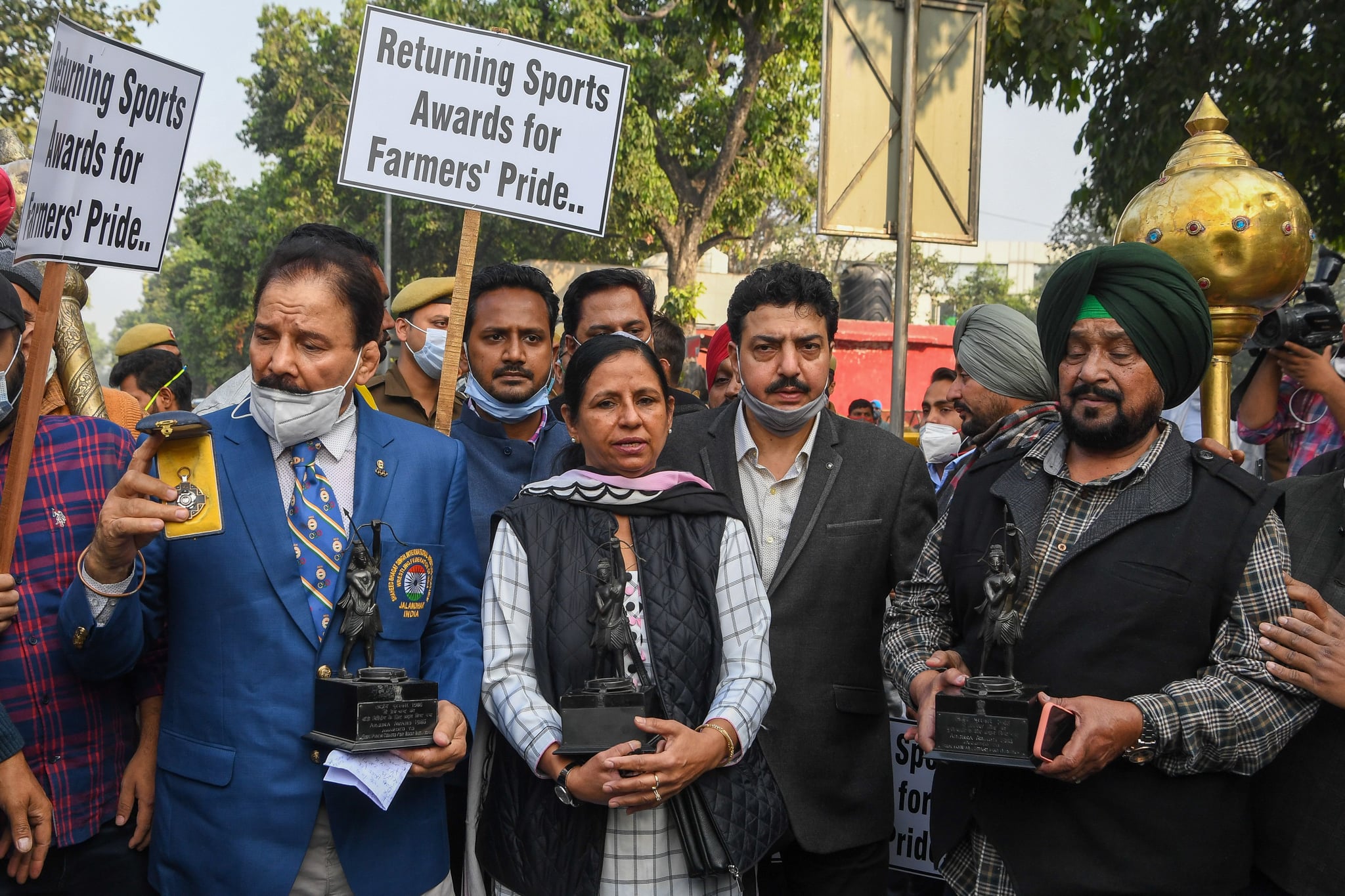 Former wrestler Kartar Singh (R) and former field hockey players Jasbir Kaur (C) and Gurmail Singh (R) pose with their trophies as they march to the the President's house to return their awards in support of the farmer's protest against the recent agricultural reforms, in New Delhi on December 7, 2020. (Photo by Prakash SINGH / AFP) (Photo by PRAKASH SINGH/AFP via Getty Images)