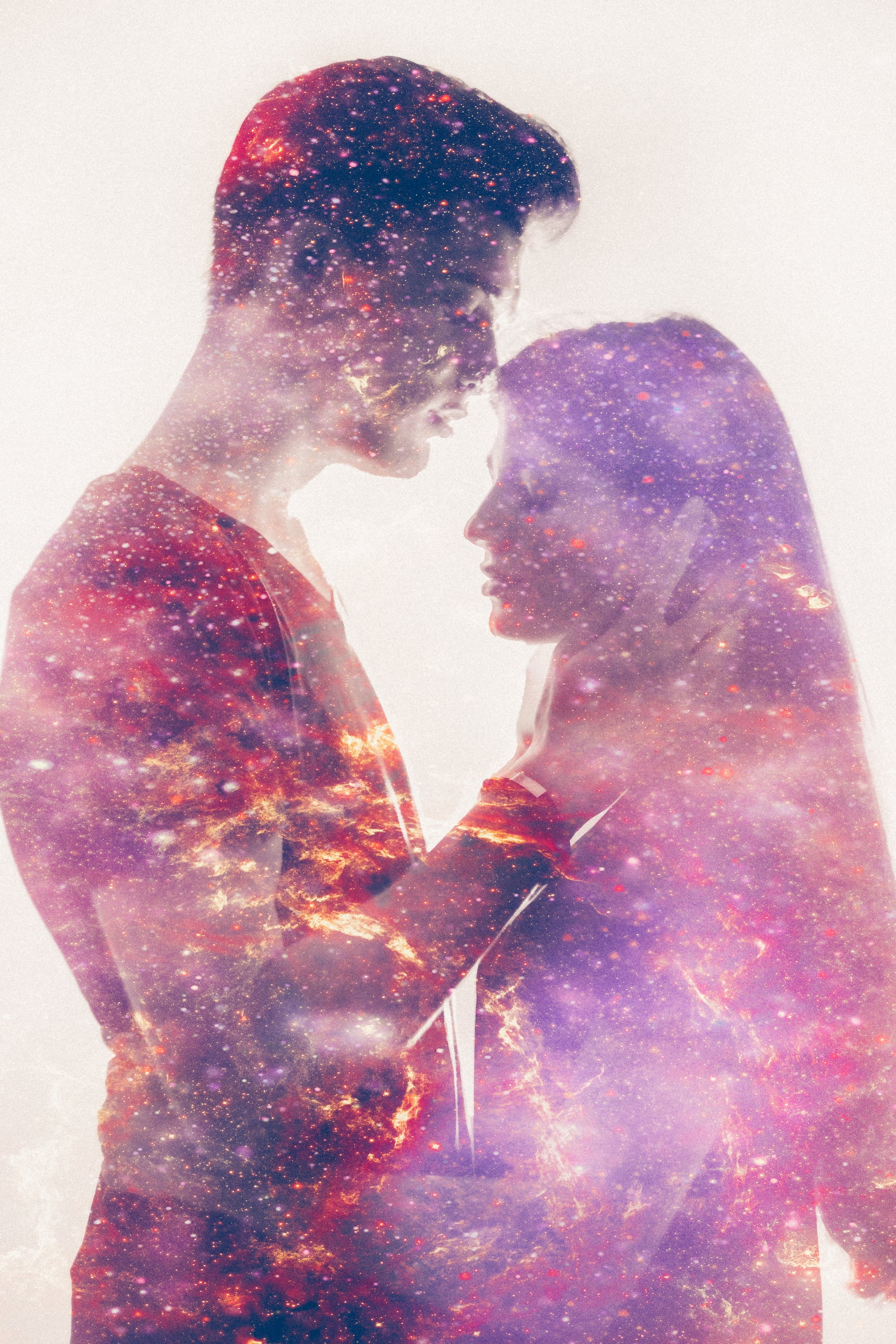 Double exposure effect with the forms of a loving couple filled in with a colourful representation of the galaxy in soft pink tones