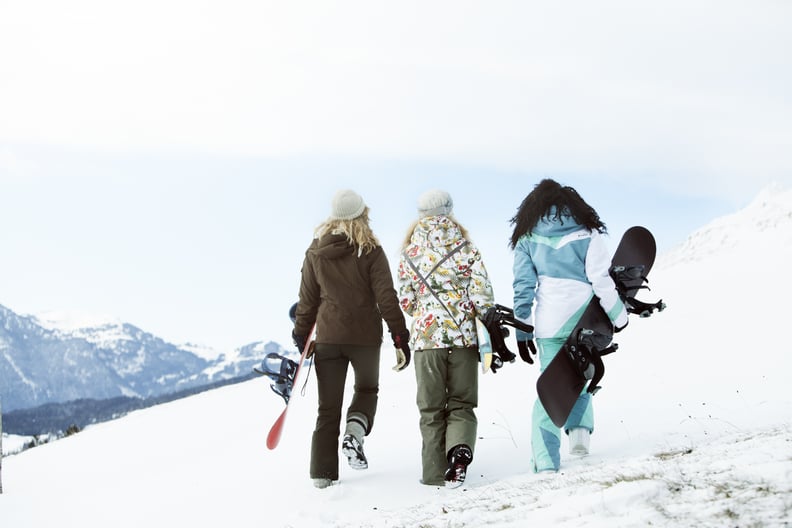 3 young women with snowboards, rear view,  on winter holiday in switzerland,