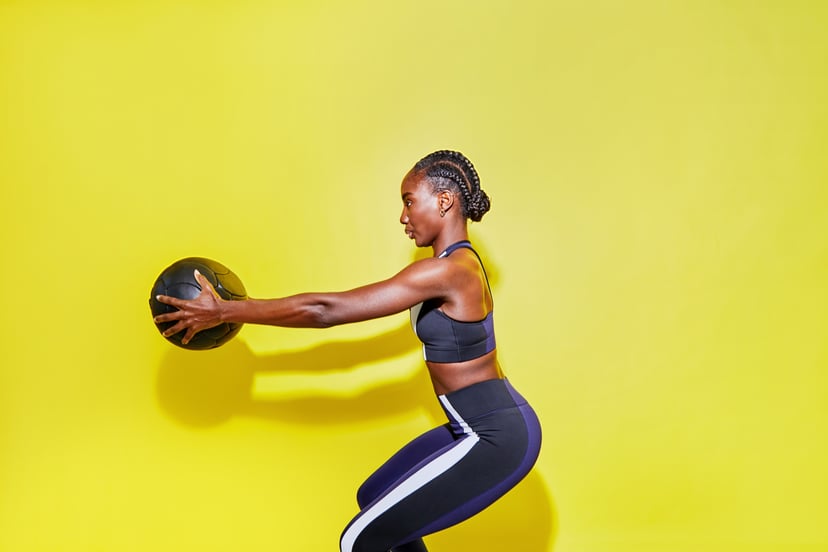 Woman does strength training to build muscle with a weighted ball.