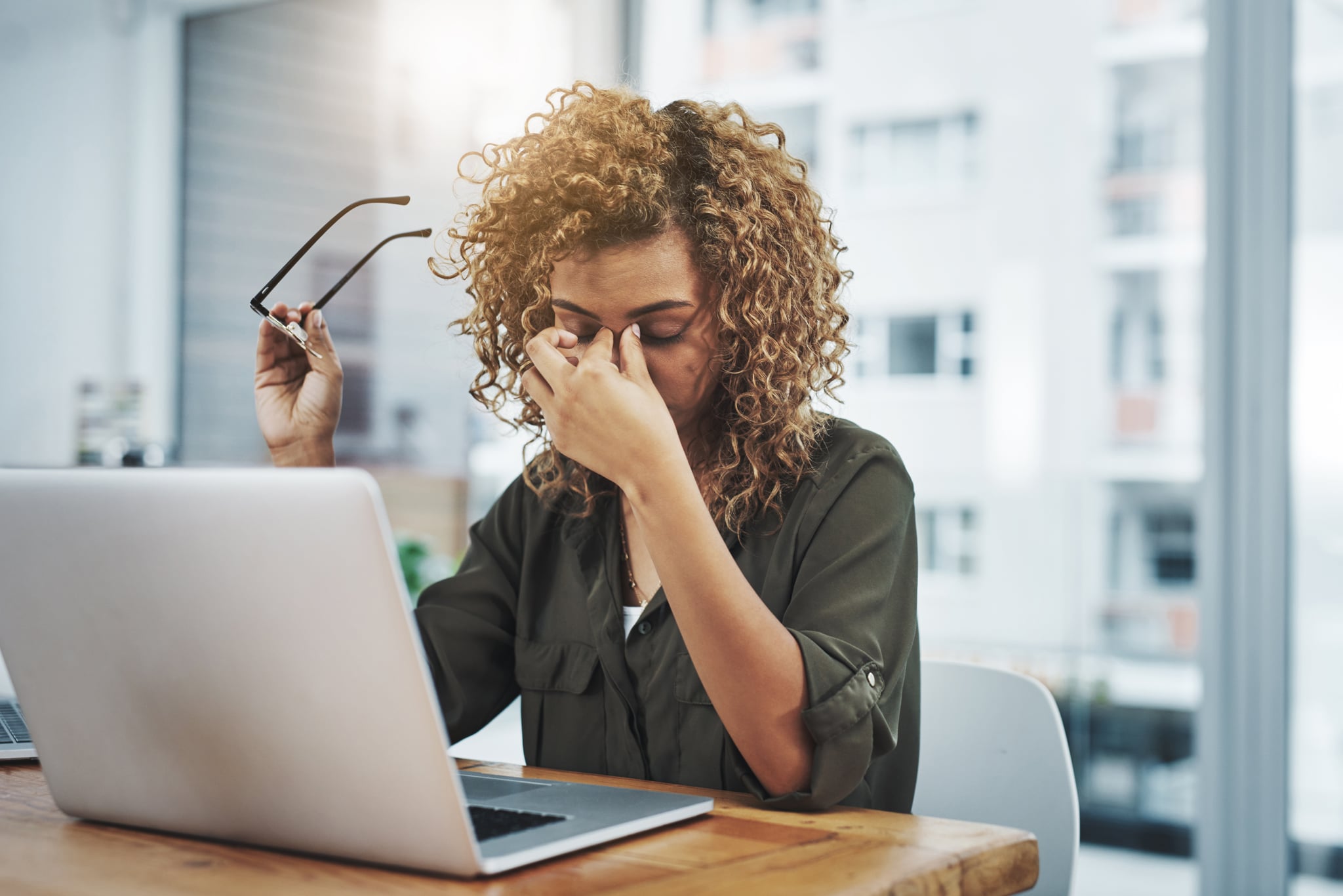 Shot of a young woman suffering from stress while using a computer at her work desk