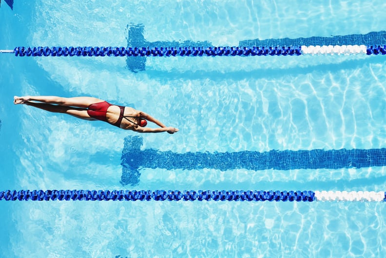 Female competitive swimmer diving into outdoor pool overhead view