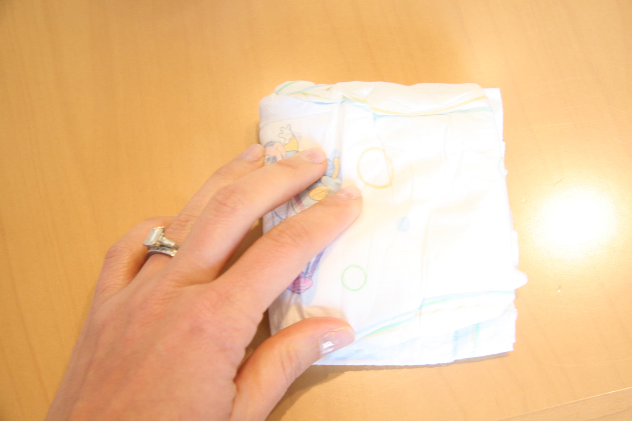 Next, fold the diapers and start placing them inside the looped ribbon.