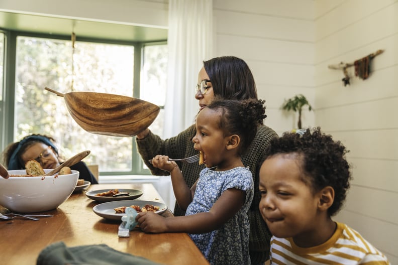 Family around dinner table eating noodles together