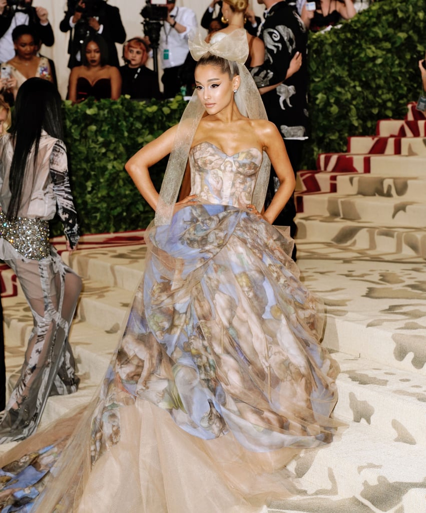 At the May 7 Met Gala, Ariana accompanied Vera Wang in a watercolour strapless gown the designer created. Appropriate for the event's "Heavenly Bodies" theme, the piece was painted with Michelangelo's "The Last Judgment" scene, which covers the altar wall of the Sistine Chapel in Vatican City. Ariana's momentous look was finished with a large tulle bow and Butani jewels.