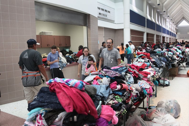 People gather by donated clothes at a shelter.