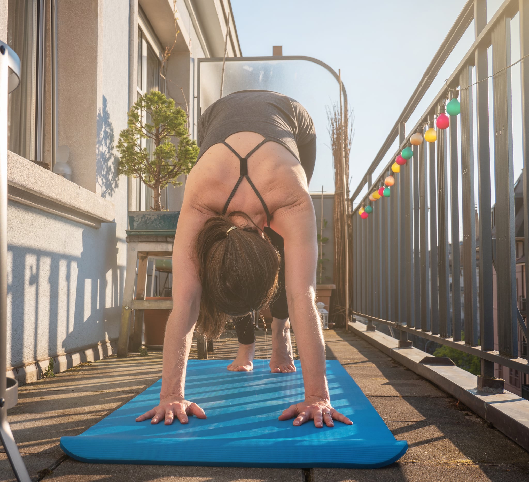 A woman practices yoga on the balcony of her apartment during the Covid-19 lock down in Geneva, Switzerland. The sun shines on the balcony as she maximizes the space available to work out from home.