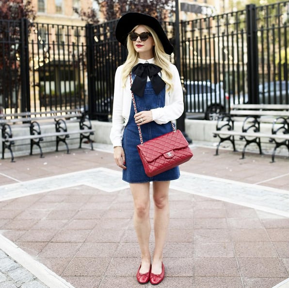 A Denim Overall Dress With a White Button-Down and Flats