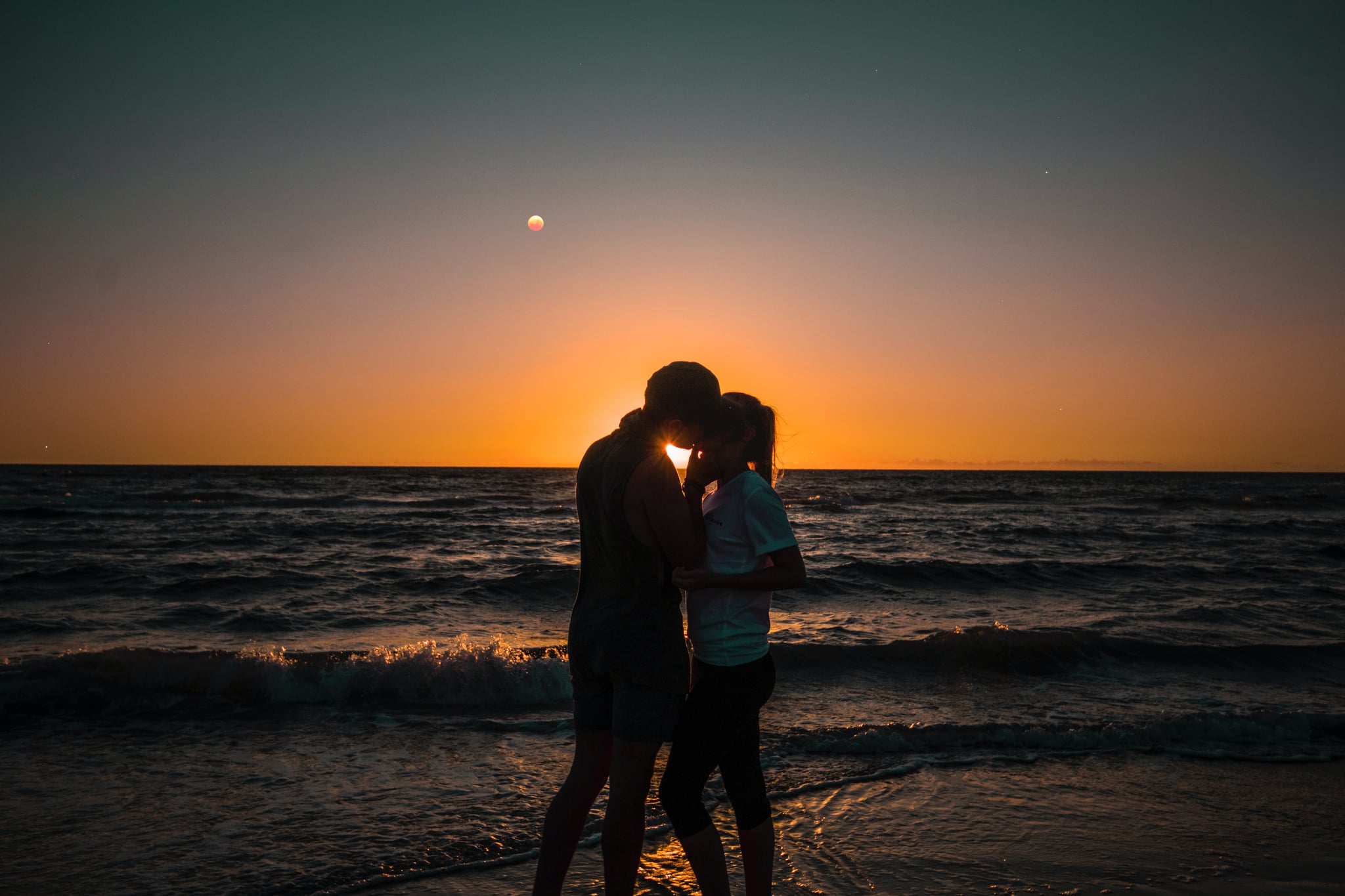 couple kissing in front of the moon signifying moon phase compatibility