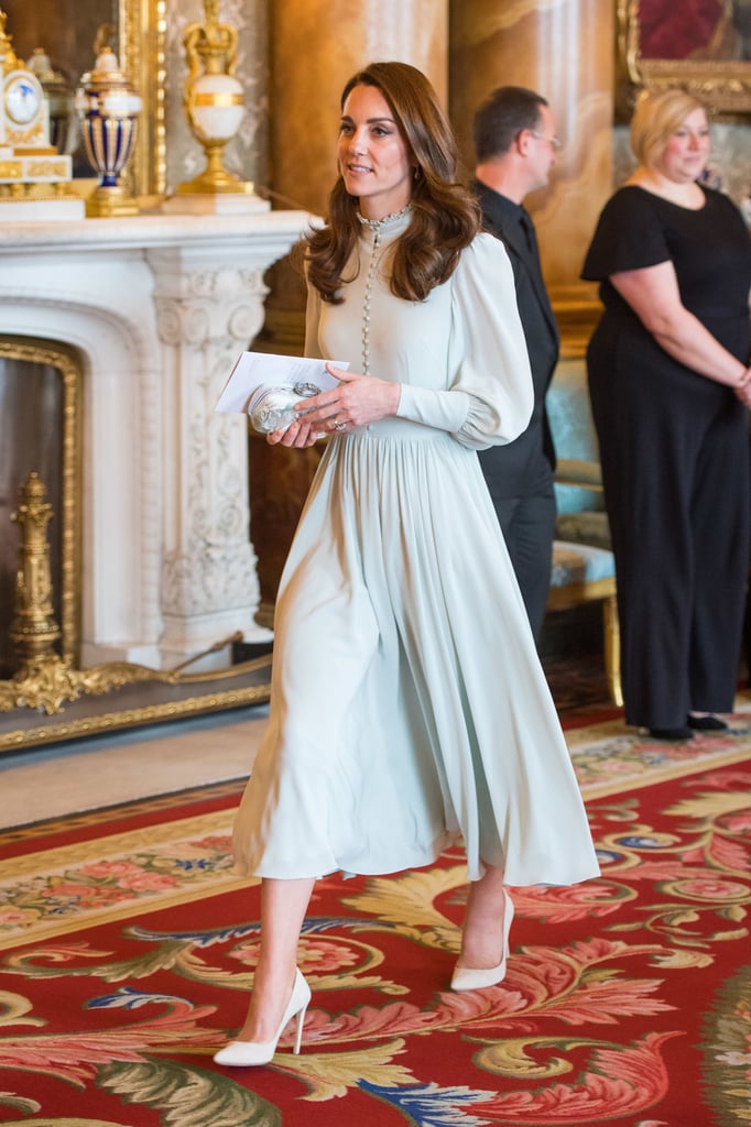 The British royal family stepped out for a celebration of Prince Charles's investiture on Tuesday, and both Kate Middleton and Meghan Markle stayed true to their personal style with their very appropriate outfit choices. While Meghan chose an intricate knee-length brocade dress and a white coat, Kate chose a longer, midi hemline, opting for a mint green dress reportedly by her private dressmaker, with a modest high neckline, long bishop sleeves, and dozens of tiny covered buttons. 
She finished the look with cream suede pumps and a brocade box clutch in the same pale hues as her dress. A pair of aquamarine drop earrings added the final touch. Take a closer look at the whole outfit ahead.

    Related:

            
            
                                    
                            

            We&apos;re Sitting Here Gazing at Kate Middleton&apos;s Glittering Dress With Wonder