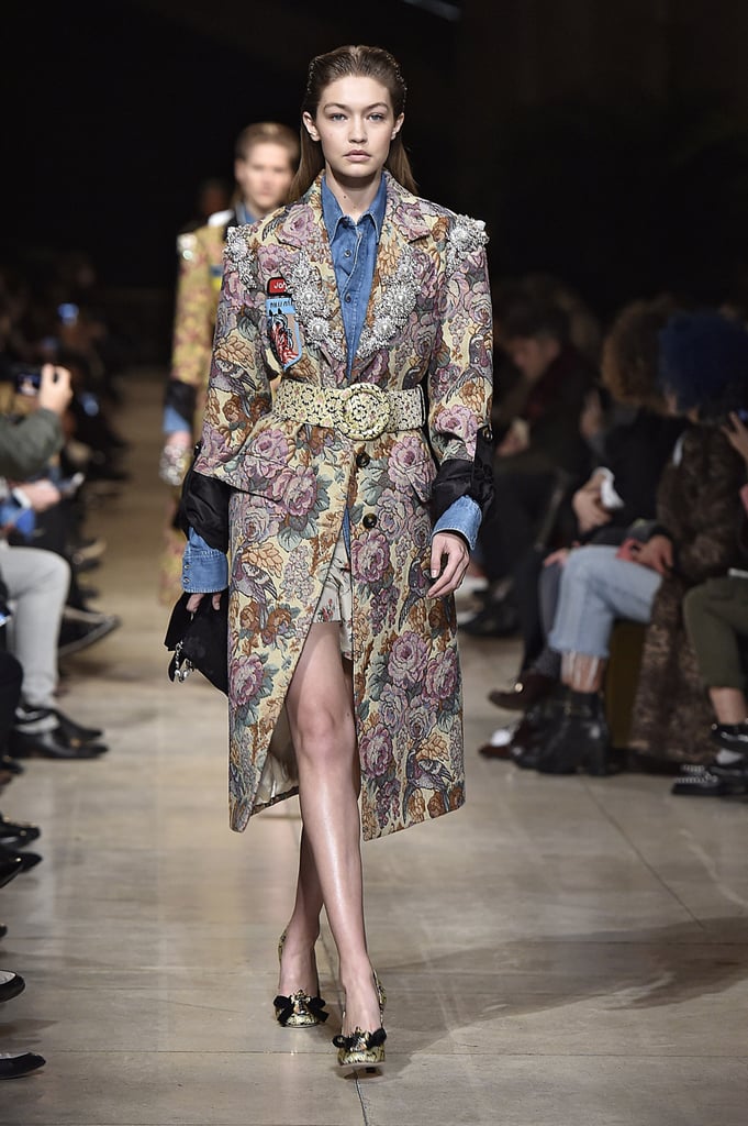 Gigi's Miu Miu outfit was full of florals. She worked a belted jacquard coat over a denim button-down and completed the look with a dainty chainstrap purse and bow-adorned heels.