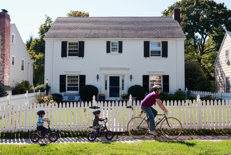 Father and twin 4-year-old sons riding bicycles in front of suburban home