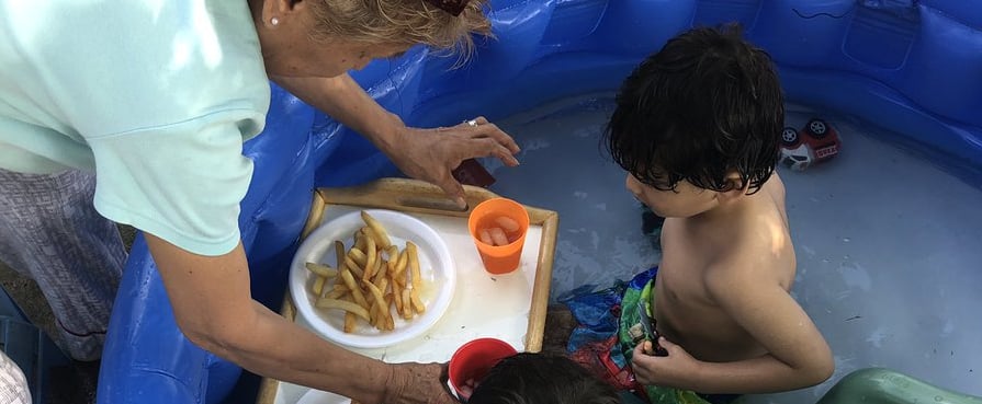 Grandma Feeds Grandkids While in the Kiddie Pool