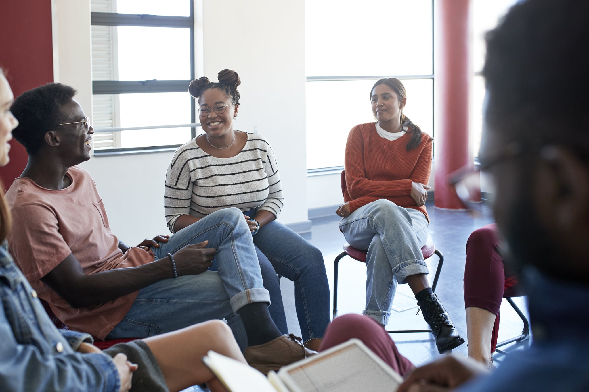 Smiling young university students sitting with instructor in classroom during psychotherapy