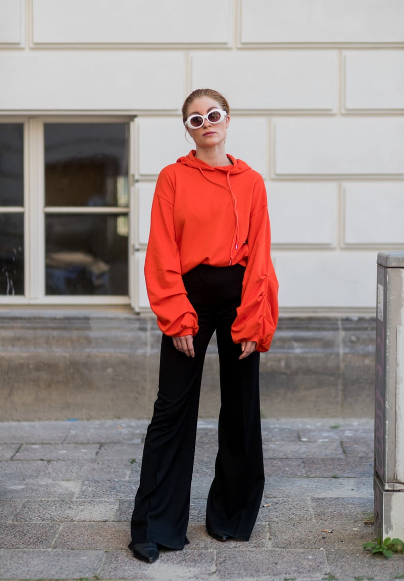 Give Off Subtle Festive Vibes by Tucking an Orange Top Into Black Bell Bottoms