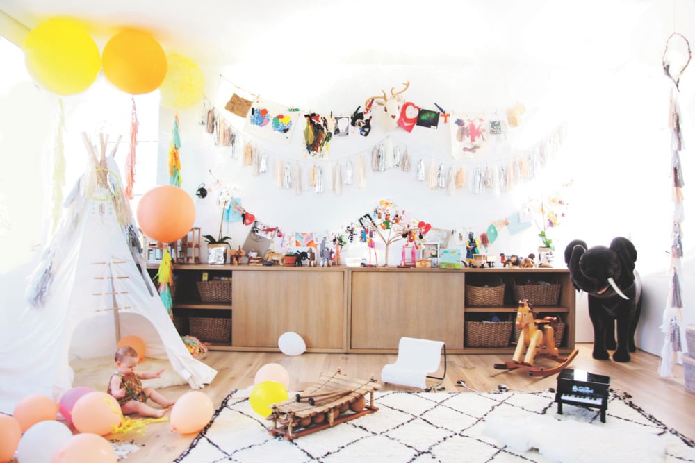 We love how steeped in light this nursery is, and it's painted in Nicole's favorite hue: white! Who can resist a tepee — here paired with playful banners and balloons? The Beni Ourain-style, lattice-design rug gives the baby a soft place to crawl on the hardwood floor.