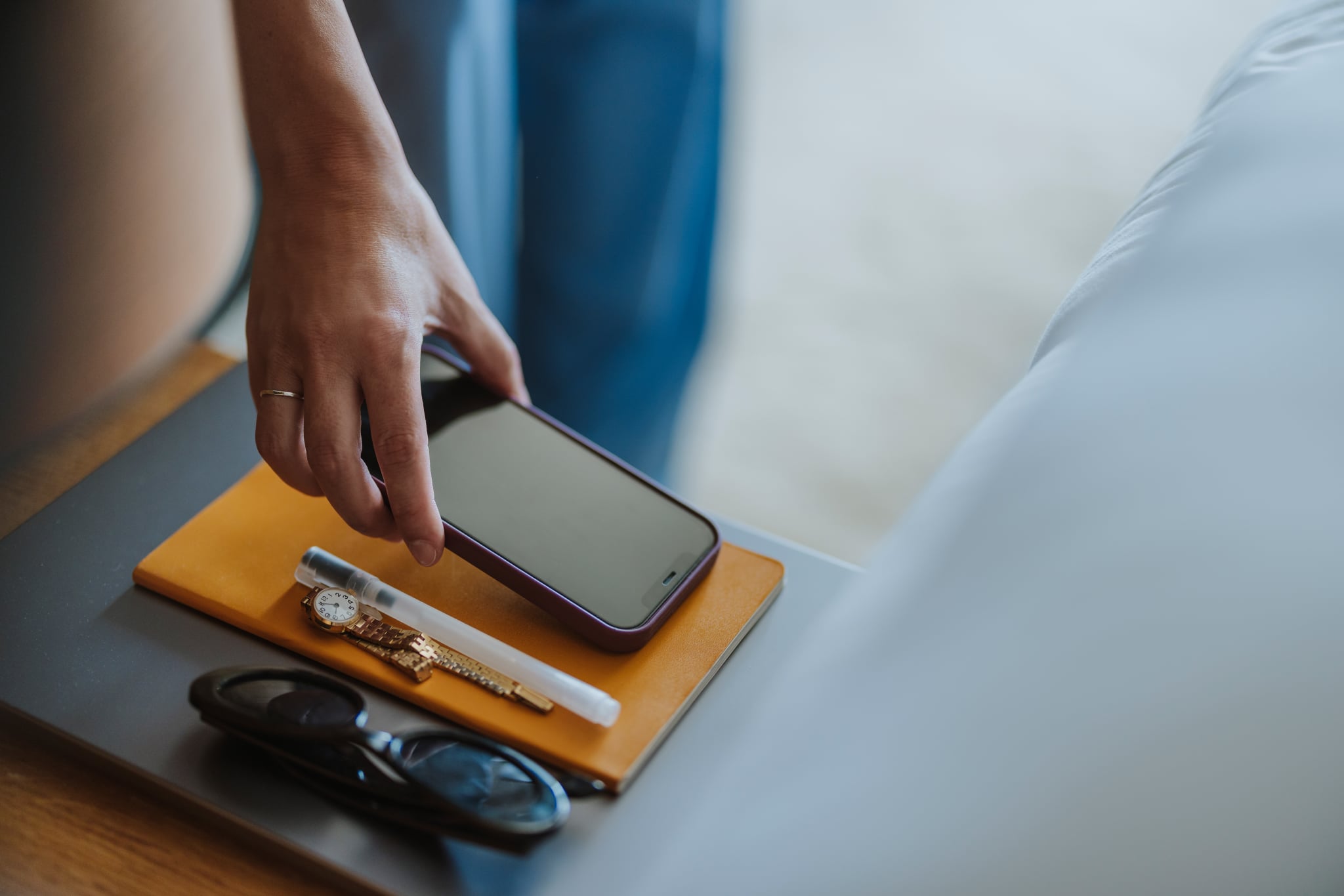 Close up shot of an unrecognizable woman picking up a smartphone from a bedside table.