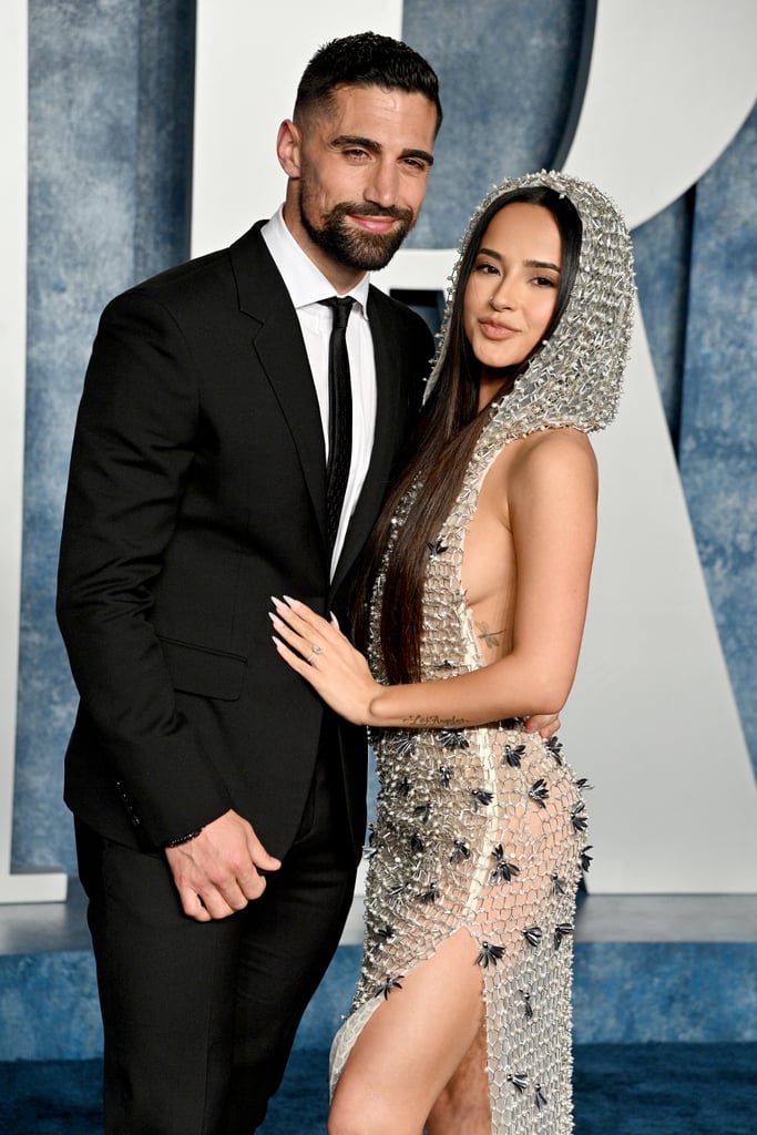 The 2023 Vanity Fair Oscars party brought out some major stars, from Megan Thee Stallion to Billie Eilish and boyfriend Jesse Rutherford, but the bash marked an extra special milestone for Becky G and Sebastian Lletget: their first joint red carpet since getting engaged. On Sunday, the couple made a sultry appearance when they arrived at the event. The 26-year-old singer kept things sexy in a chain-mail dress, while the 30-year-old FC Dallas soccer star looked dapped in a black suit.
Becky G and Lletget have been together since June 2016. In a previous interview with POPSUGAR, Becky G revealed that she was the one who made the first move in their relationship. "I remember mutual friends [Jordan and Naomi Scott] kind of talking and putting in groundwork on each end. Jordan had played with Sebastian in the past, and his wife, Naomi, was my castmate in the movie that I was filming at the time," she explained. "They kept playing cupid, and they didn't tell either one of us who we were or what we did because they didn't want us to fall under the pressure of, 'Oh, superstar dating athlete! Oh, perfect match made in heaven,' because they knew who we were as people."
"I followed him on Twitter and he followed me back, and I remember it was like this ghost-y, 'I know you exist, you know I exist,' thing," she added. "I waited a couple days after my 19th birthday just to sound older, which is so funny to me now . . . he was like 23 at the time . . . so I slid in the DM real hard and I was like, 'Hi, what's up?' So groundbreaking!"
The couple announced their engagement this past December with photos from Lletget's oceanside proposal in Manhattan Beach, CA.  "Our spot forever," they captioned the joint Instagram post. While speaking with People earlier this month, Becky G revealed she has not started wedding planning, adding, "I don't know, I might just go make an appointment, go to the courthouse. Call it a day. Throw a party later." Or, she may also "throw a big ass Mexican wedding," she told the outlet. "We said for sure they'll be mariachi — whatever we do there has to be mariachi — there has to be good food and good asado because he's Argentinian, I'm Mexican so for sure that and of course our families. I think as we develop those conversations, we'll see where it takes us."
As we wait for more updates on Becky G and Lletget's upcoming nuptials, keep reading to see their night out at the Vanity Fair Oscars party. 

    Related:

            
            
                                    
                            

            Becky G Celebrates Her 26th Birthday in a Sheer Dress and Black Wedding Veil