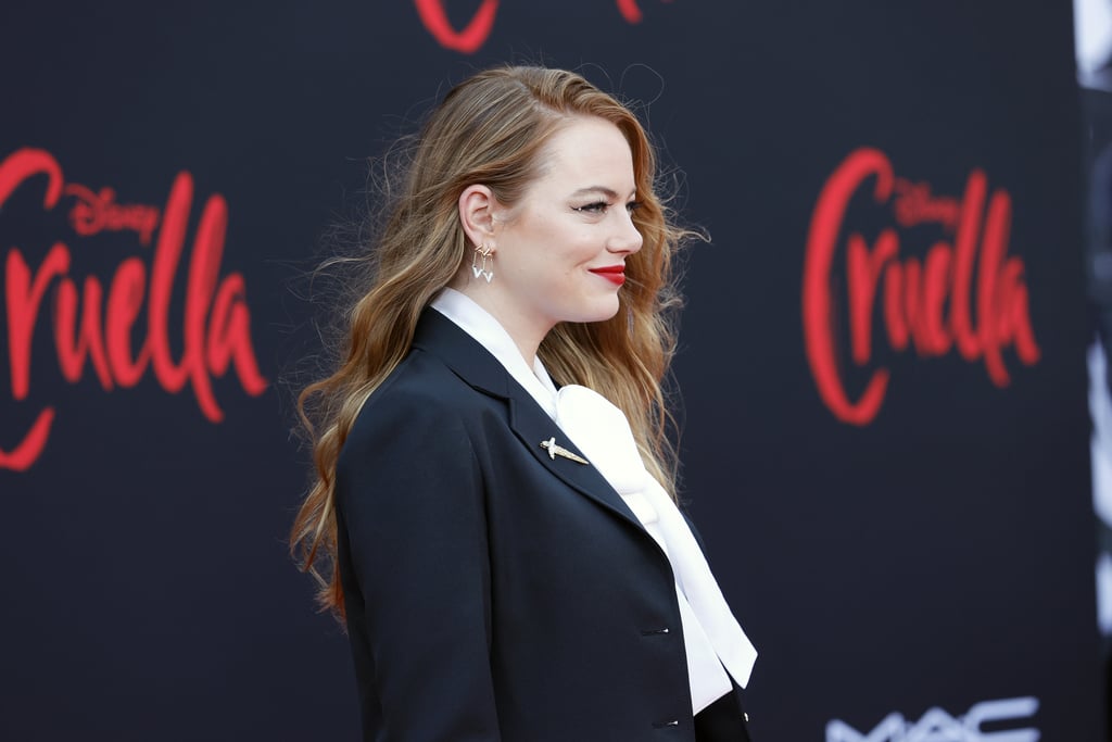 Emma Stone's appearance at the Cruella premiere was one big homage to the wickedly chic villain. For the Los Angeles red carpet event on May 18, the actress, who welcomed her first child earlier this year in March, wore a Louis Vuitton outfit in Cruella de Vil's signature colors of black, white, and red. 
Styled by Petra Flannery, the look consisted of a black suit with chain-link details, a white pussy-bow blouse, black pointed-toe pumps, a bright red box clutch, dangly earrings, and a dagger brooch made of over 150 diamonds, including a yellow pear diamond. Whereas viewers are used to seeing the character in a black dress and big (Dalmatian) fur coat, Emma's outfit is a more modern take, much like the prequel movie, which shows Cruella as an aspiring fashion designer not yet jaded. 

    Related:

            
            
                                    
                            

            Glenn Close Made Sure Her 101 Dalmatians Contract Included Keeping Every Single Cruella de Vil Costume