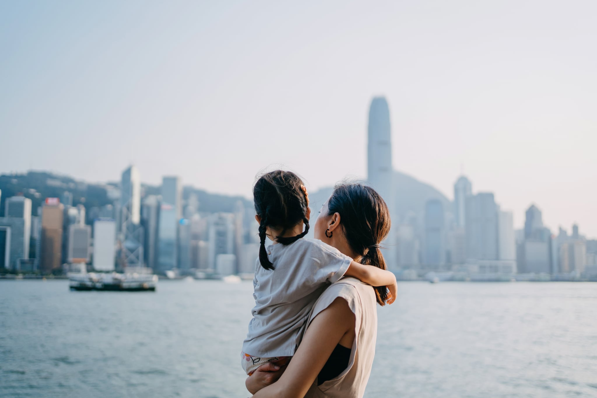 Woman and daughter looking out over the ocean and toward the city