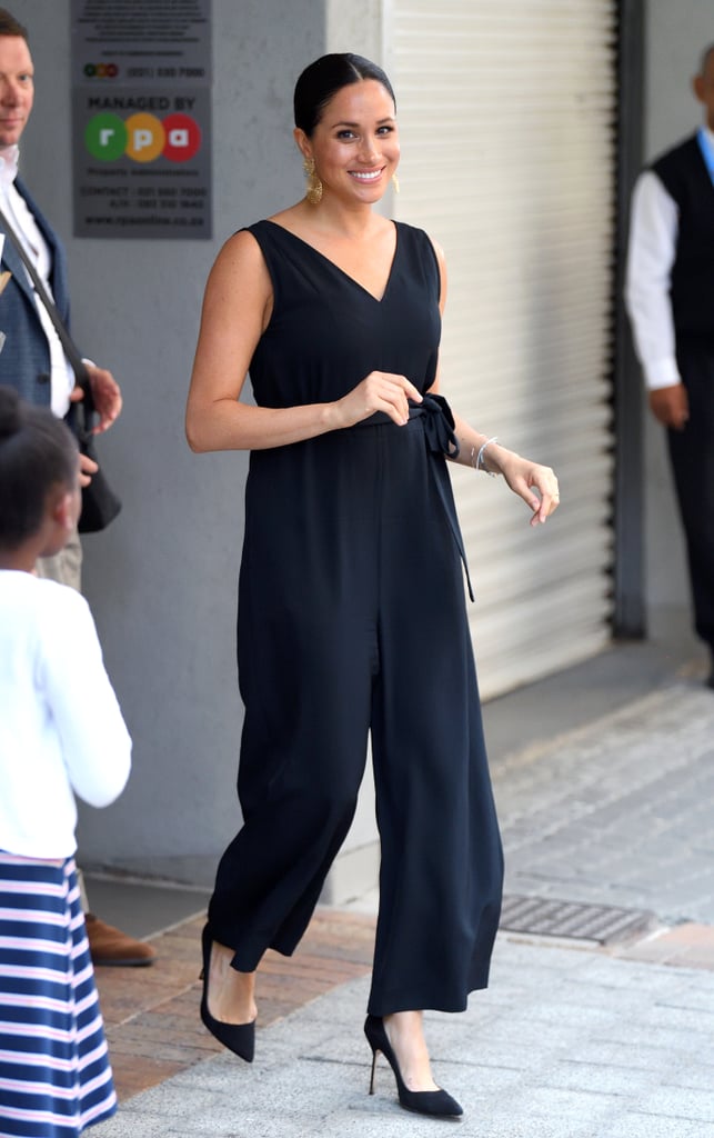 Meghan, Duchess of Sussex Wears An Everlane Jumpsuit with Manolo Blahnik Pumps, and Gold Earrings