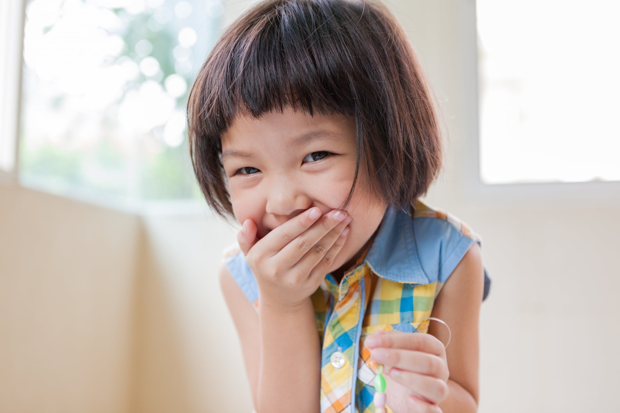 laughing girl playing with beads and a string at the table