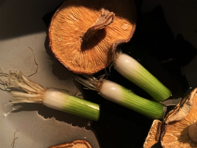 pot of water with shiitake mushrooms, green onion roots, and Kombu