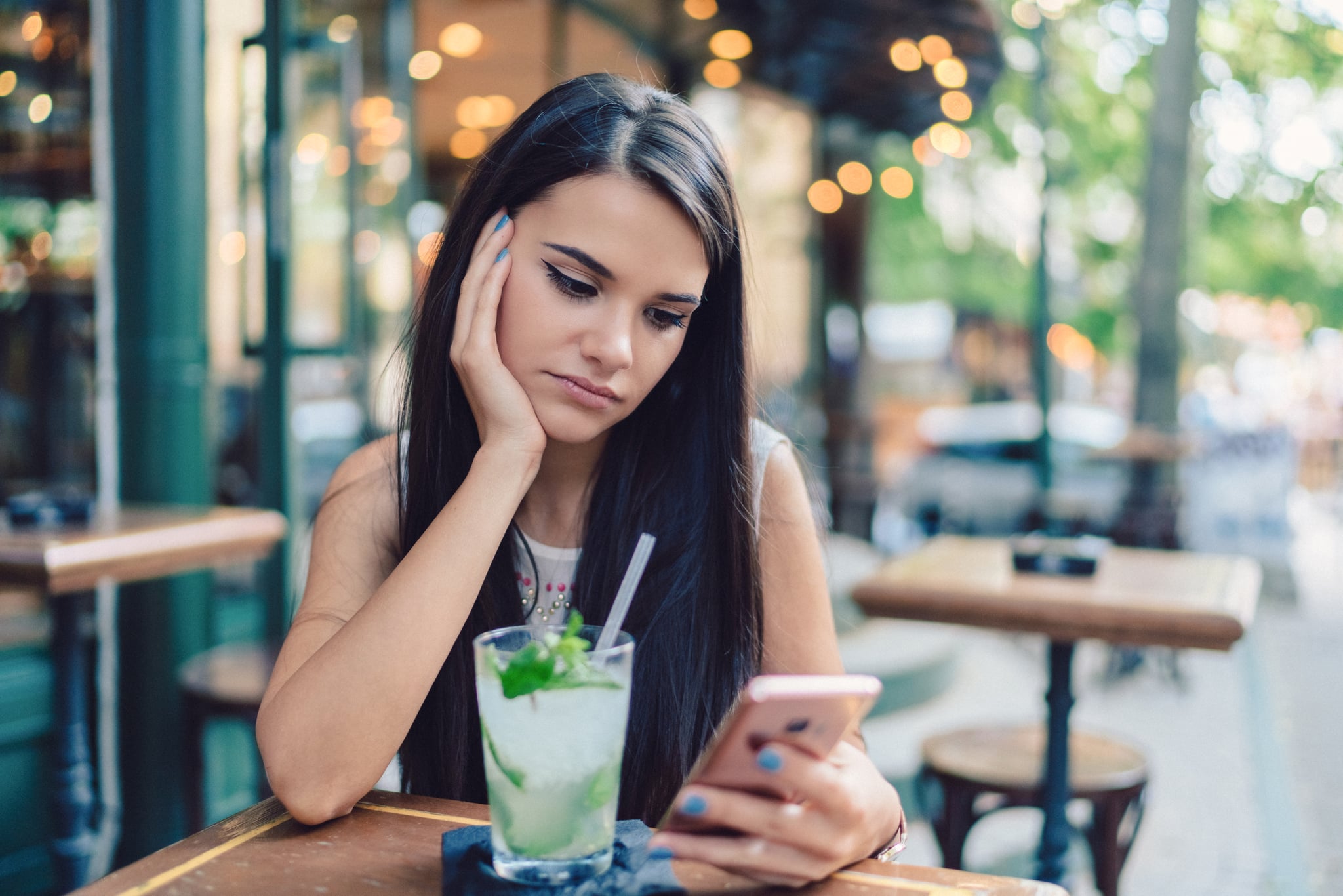 Thoughtful woman at sidewalk cafe drinking cold cocktails