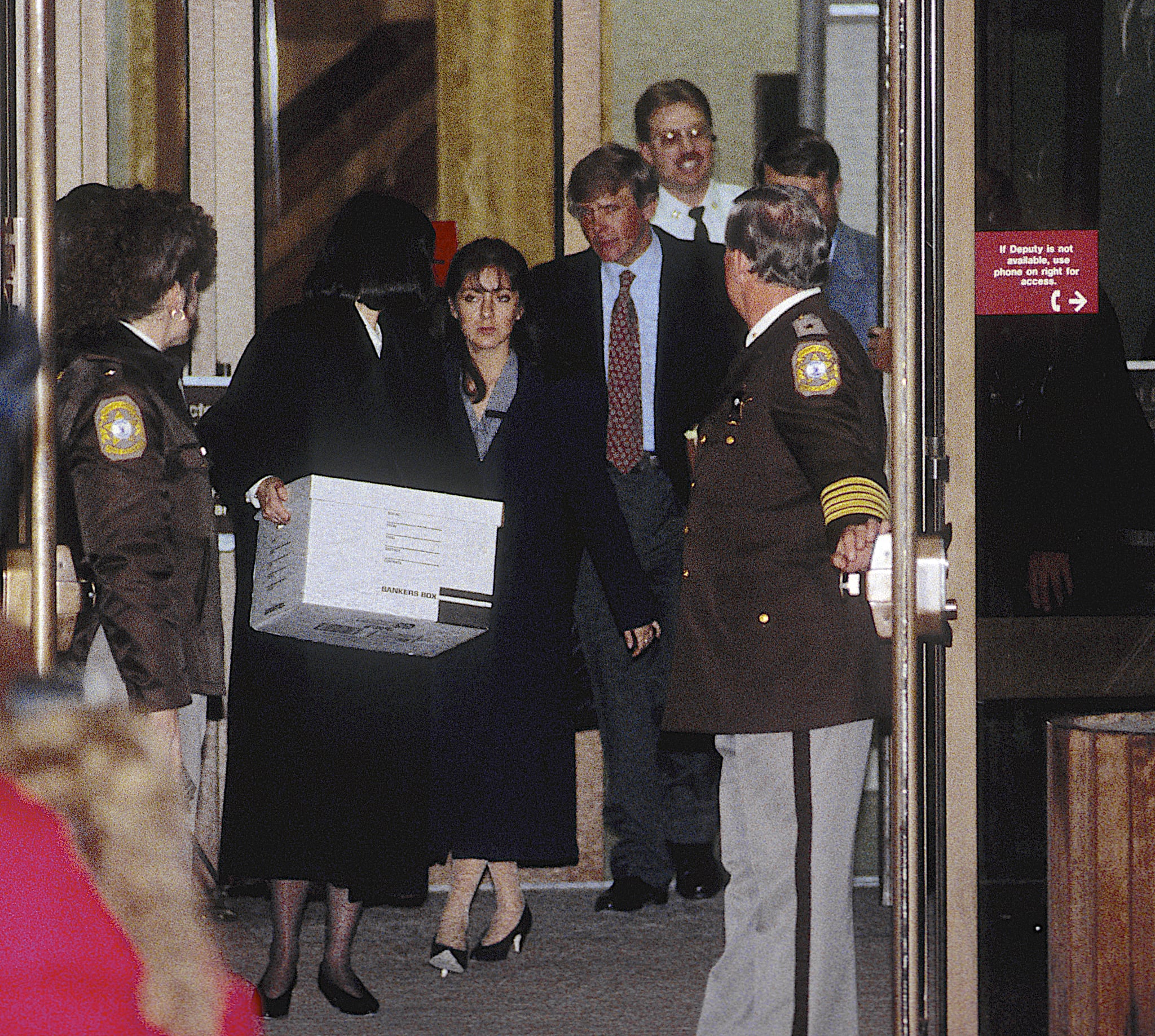 On the second day of her trial, the accused, Lorena Bobbitt (center), and her lawyers, Lisa Kemler (with box), Blair Howard (red tie), and James Lowe (right, mostly obscured behind deputy), leave the Prince William County Courthouse, Manassas, Virginia, January 11, 1994. Bobbitt was accused (and later acquitted) in the malicious wounding of her husband when she, two years earlier, had severed his penis with a kitchen knife. (Photo by Mark Reinstein/Getty Images)