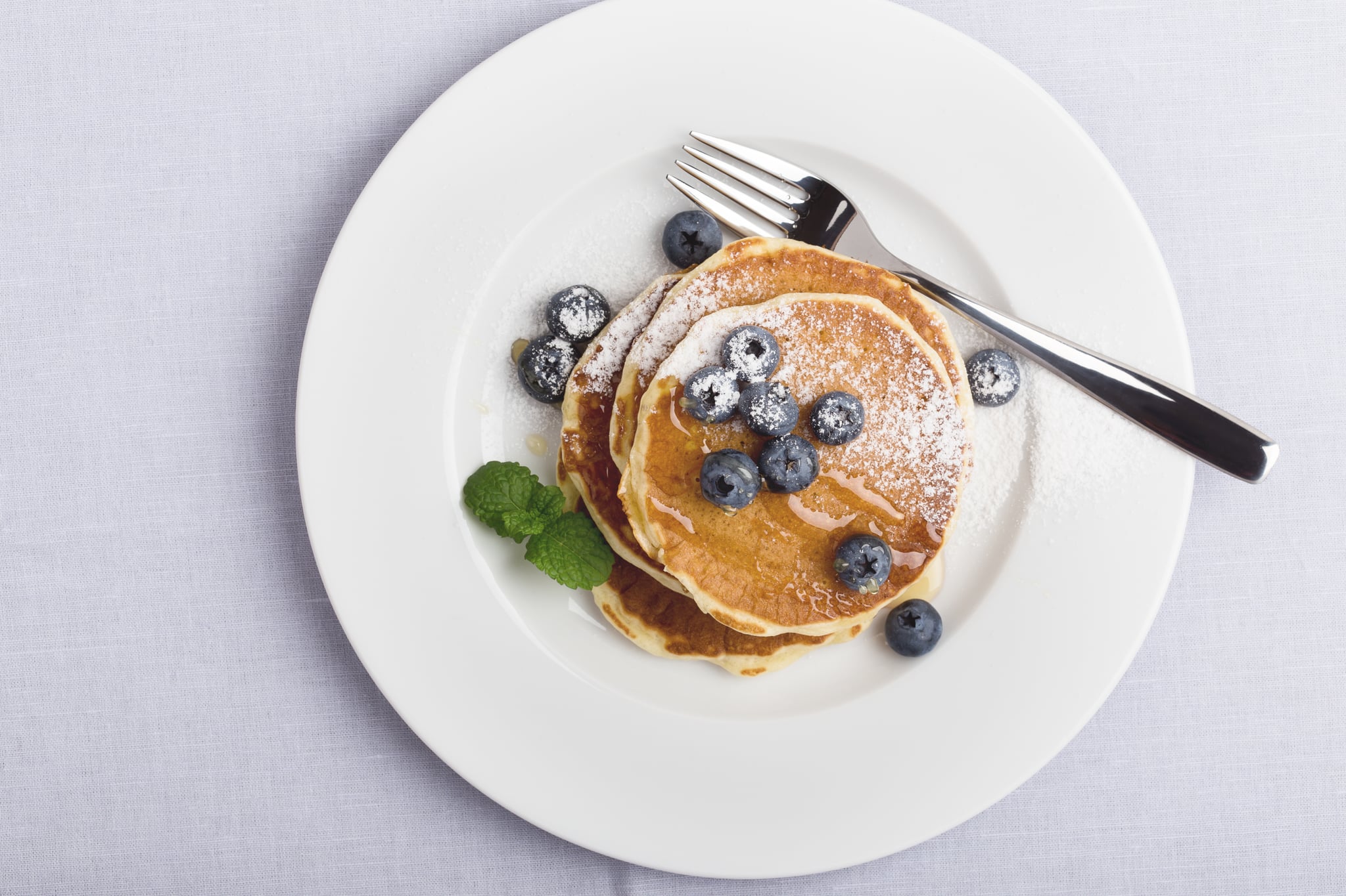 Blueberry pancakes on white plate viewed from above