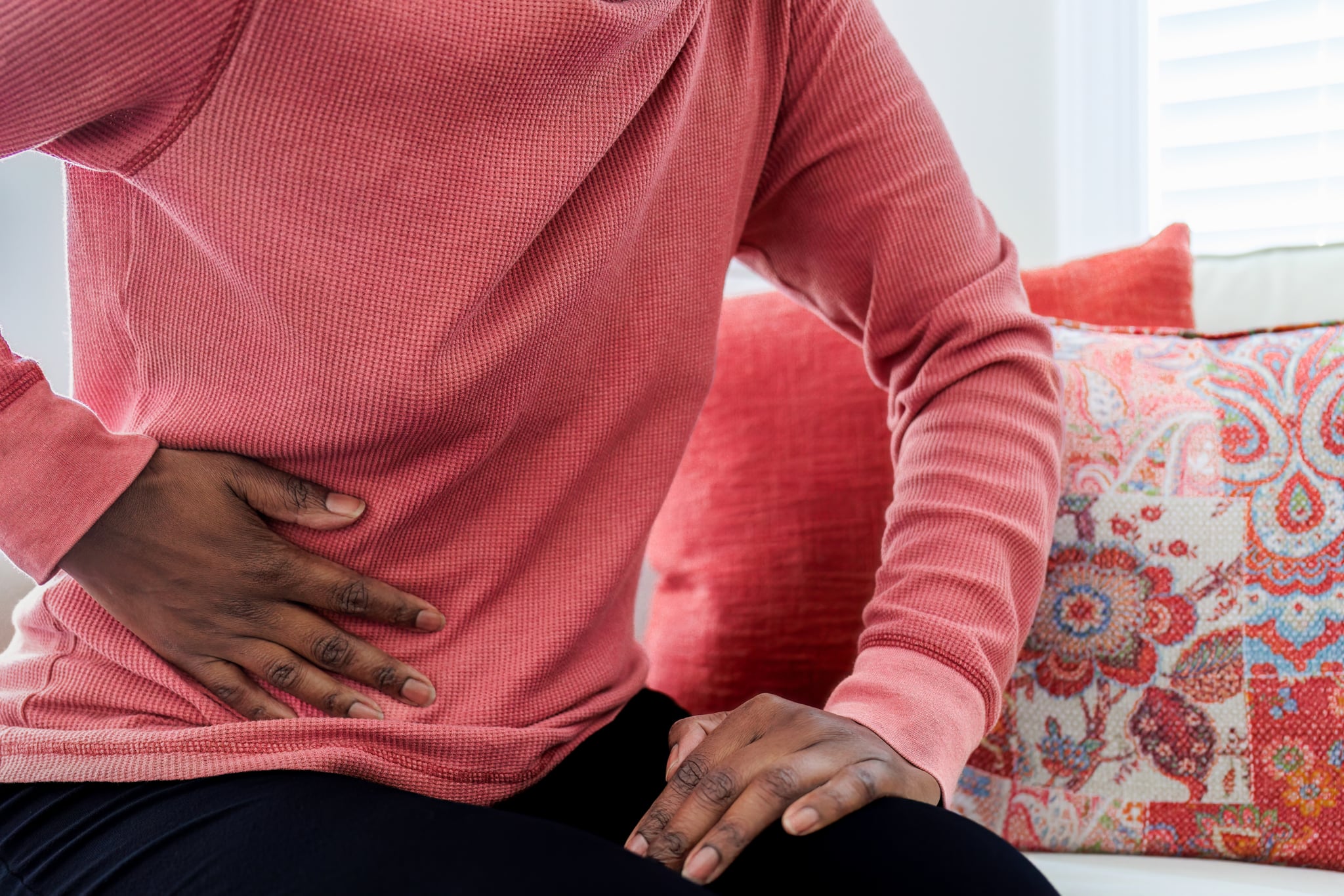 Woman sitting on couch with pain from a UTI or yeast infection.