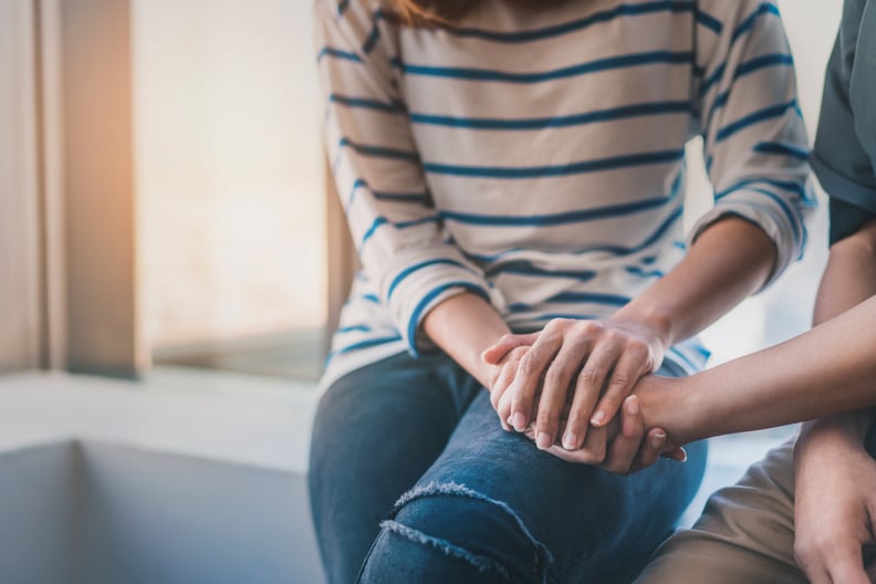 Woman holding hand compassionately with someone else