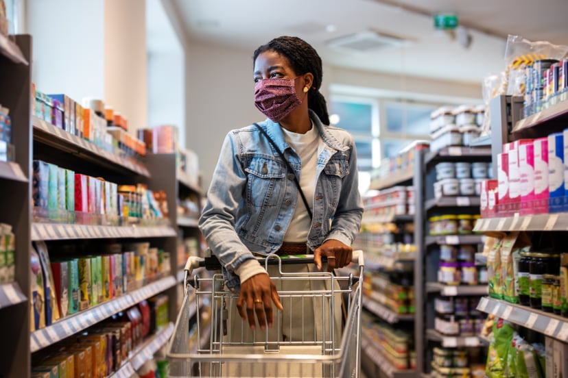 African woman wearing protective face mask buying grocery at a supermarket. Female customer shopping at a local grocery store.