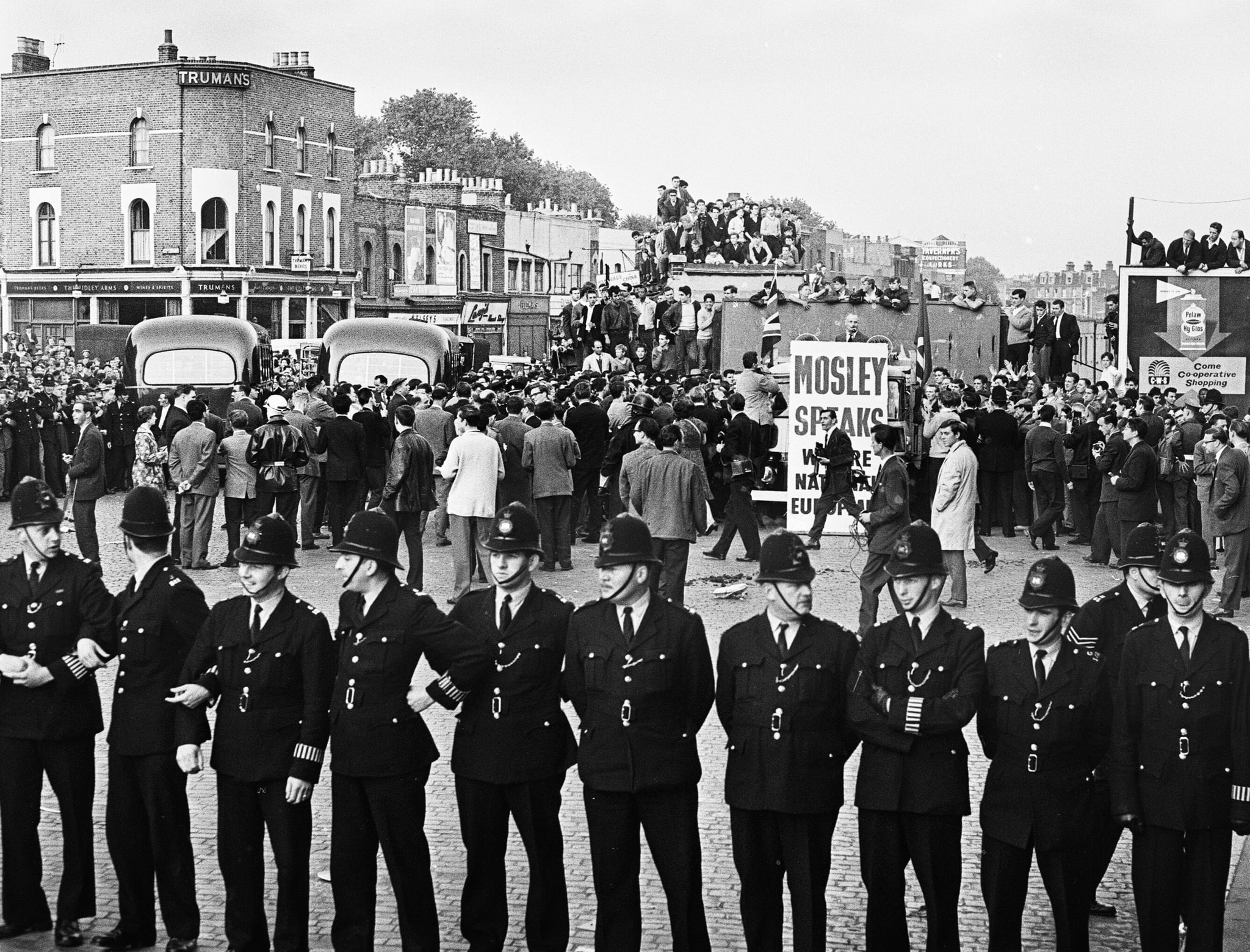 Large crowd gathered in Ridley Road E8 to demonstrate against former fascist leader Sir Oswald Mosley and members of his anti-Semitic Blackshirt group who had planned a rally in London's East End. Mosley and his anti-Semitic Blackshirt were assaulted and punched to the ground as soon as his meeting opened at Ridley Road, Dalston. Police closed the meeting within the first three minutes and made 54 arrests, one which was Sir Oswald's son Max., our picture Shows: Police presence at the rally, 31st July 1962. (Photo by Alisdair MacDonald/Mirrorpix/Getty Images)