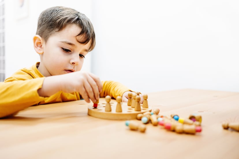Little kid playing a board game during education therapy