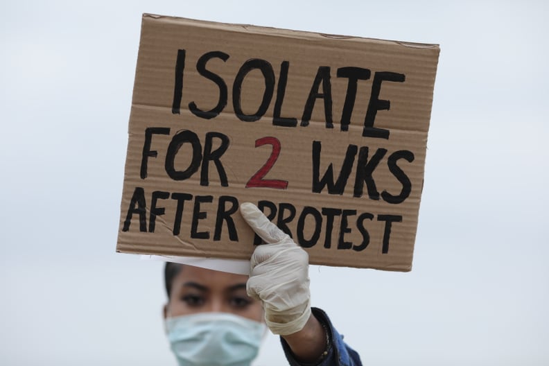 LONDON, ENGLAND - JUNE 03: A protester wearing a face mask holds up a sign saying 'Isolate for 2 weeks after protest' during a Black Lives Matter protest in Hyde Park on June 3, 2020 in London, United Kingdom. The death of an African-American man, George 