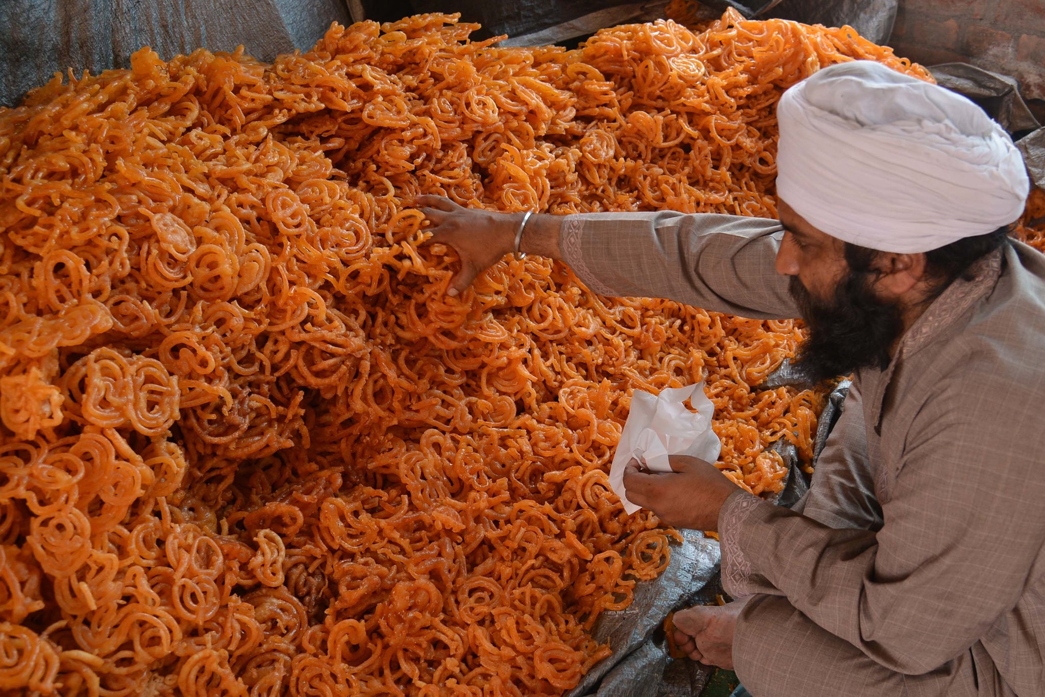 An Indian Sikh devotee puts 'Jalebi' sweets in plastic packets for free distribution to devotees during the Baisakhi festival celebrations held at Langar Ghar, a community hall at the Golden temple in Amritsar on April 14, 2015. Baisakhi, which is celebrated in the Punjab region, coincides with other festivals celebrated on the first day of Vaisakh, in some regions of India such as Puthandu, the Tamil New Year.  Baisakhi is especially important for the Sikh community as it marks the establishment of the Khalsa.  AFP PHOTO / NARINDER NANU        (Photo credit should read NARINDER NANU/AFP via Getty Images)