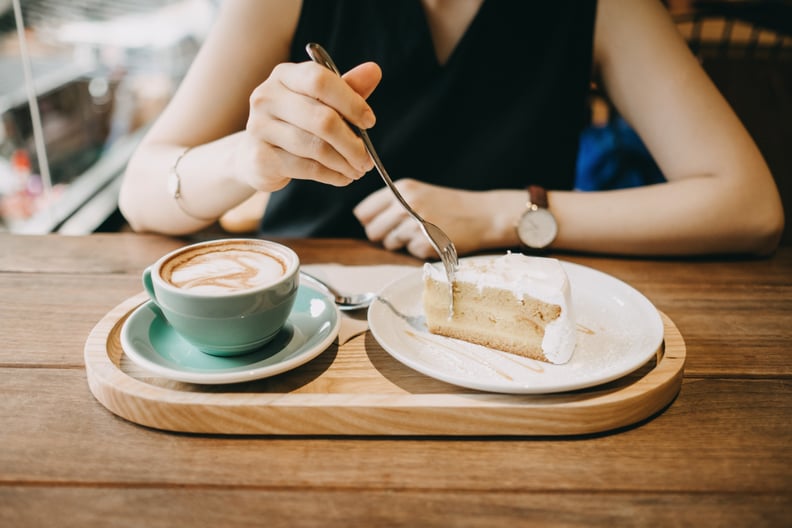 Woman having a relax time eating a slice of cake and having coffee in cafe