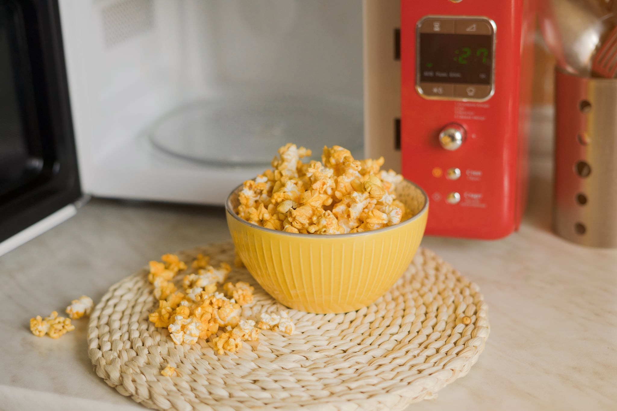 Popcorn is taken out of the microwave in the kitchen.